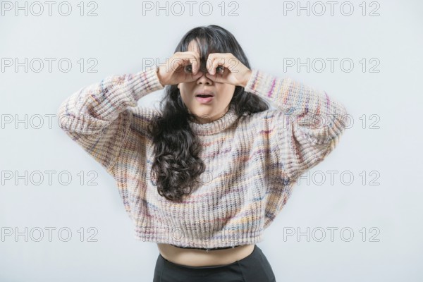 Asian woman making binoculars gesture isolated. Curious asian girl making binoculars gesture looking through fingers
