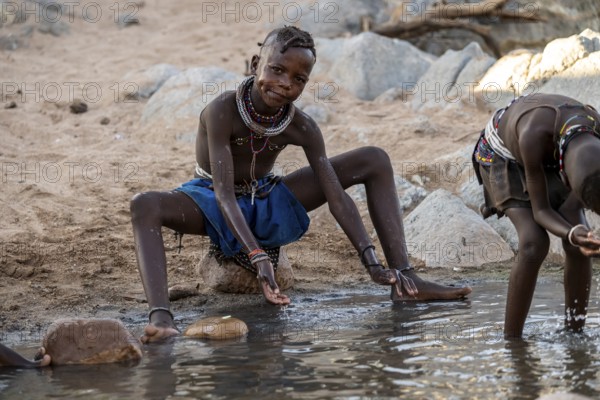 Himba child washing with water on a river, traditional Himba, Kaokoveld, Kunene, Namibia