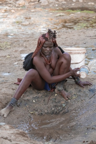 Himba scooping water at water source, traditional Himba, Kaokoveld, Kunene, Namibia