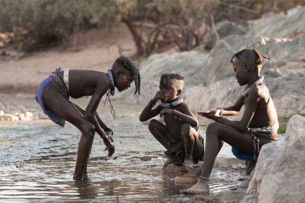 Himba children washing with water on a river, traditional Himba, Kaokoveld, Kunene, Namibia
