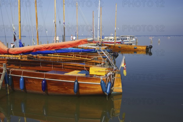 Several yachts are moored on the water in a quiet harbor, Steinhude Studer Meer