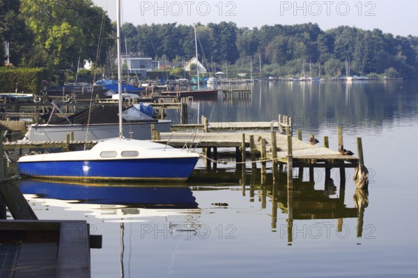 A sailboat anchors on a wooden pier in a quiet harbor on Lake Steinhude, Steinhude