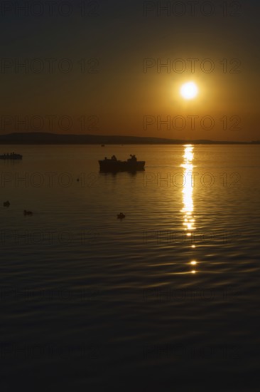 Sunset over the Steinhuder Meer with boat and reflections, quiet atmosphere, Steinhude