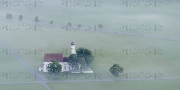 St. Coloman pilgrimage church in front of sunrise in autumn fog, Königswinkel, Ostallgäu, Allgäu, Bavaria, Germany