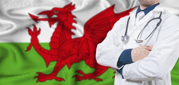 Wales healthcare concept. Male doctor on Welsh flag. Doctor with crossed arms on Wales flag