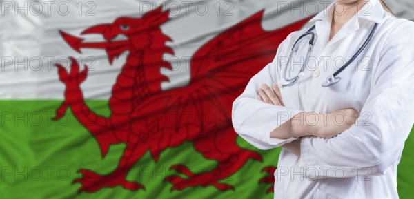 Doctor with crossed arms on Wales flag. Welsh health and care concept. Female doctor on Wales flag