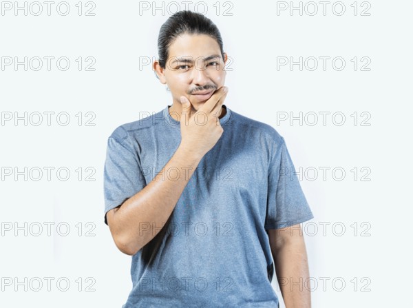 Pensive person rubbing chin with doubtful expression. Thoughtful young man rubbing his chin looking at camera isolated