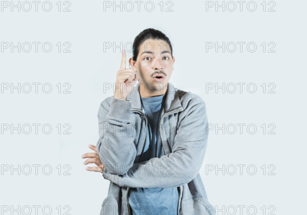 Surprised guy pointing a promotion up isolated. Surprised asian man pointing a discount up on isolated background