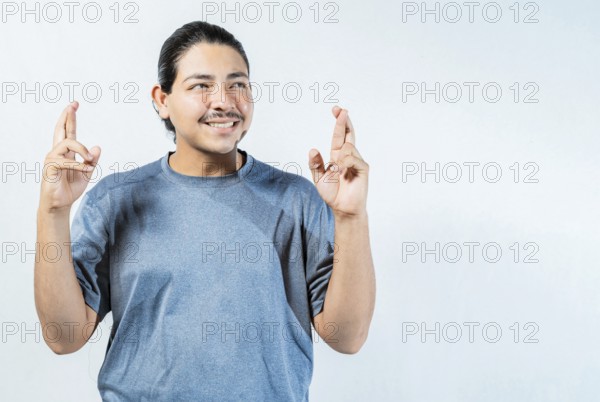 Hopeful man making a wish with fingers isolated. Optimistic guy smiling and making a wish isolated