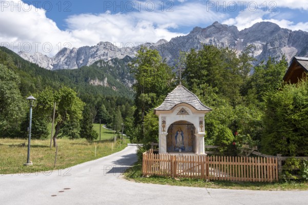 Small trail chapel with the Slovenian Alps in the background, mountaineering village Zgornje Jezersko, Slovenia