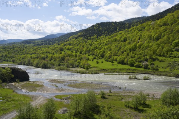 A quiet river surrounded by green hills and trees under a partly cloudy blue sky, Kvabliani River near Adigeni, Samtskhe-Javakheti region, Samtskhe-Javakheti, Georgia