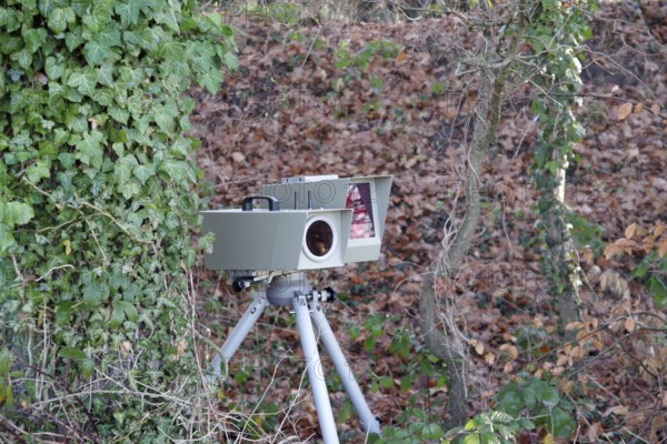 Radar meter, lightning system, traffic monitoring, speed control, speed shifter, A mobile radar system with photo camera is hidden between trees on the side of the road