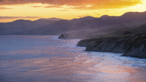 Wairarapa coast at sunset. Sea, mountains, backlight. Castlepoint, Wairarapa Coast, Wellington Region, North Island, New Zealand