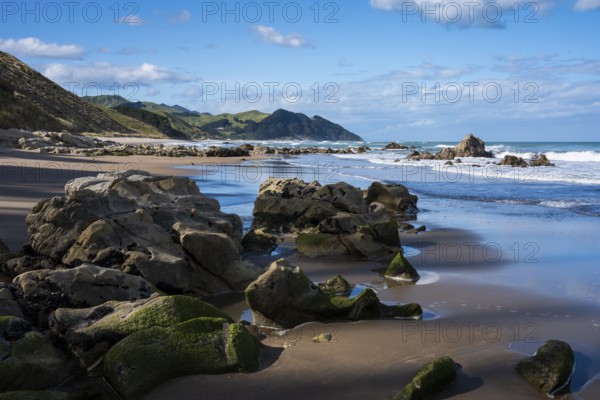 Castlepoint Beach, ocean, sandy beach, rocks, mountains. Castlepoint, Wairarapa Coast, Wellington Region, North Island, New Zealand