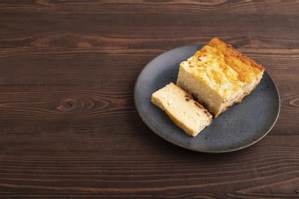 ?ottage cheese ?asserole, Curd cake, with dried apricots and raisins on brown wooden background, side view, copy space, minimalism