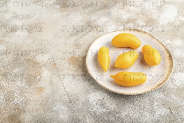 Yellow tomatoes on plate on brown concrete background. Side view, copy space. healthy food, vegetable, minimalism