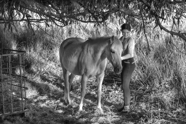 Young girl with her horse in the pasture, black and white, Othenstorf, Mecklenburg-Western Pomerania, Germany
