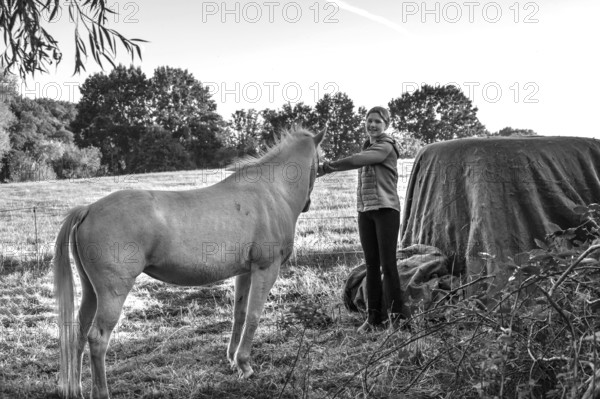 Young girl with her white horse in the pasture, black and white, Othenstorf, Mecklenburg-Western Pomerania, Germany