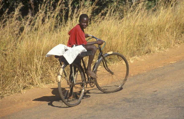 Boy riding a bicycle on a country road, Zambia, Africa, June 2000, vintage, retro, old, historic