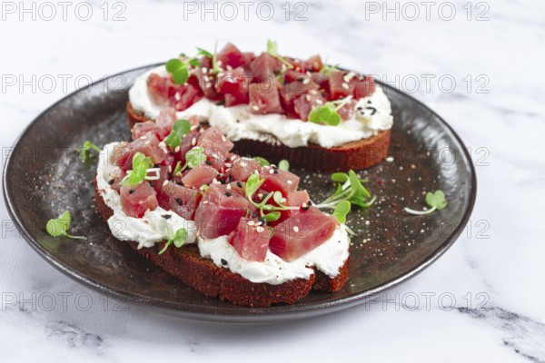 Sandwiches, rye bread with cream cheese, sliced tuna fillet with herbs, breakfast on a black plate, homemade