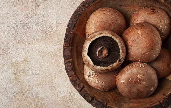 Fresh Portobello mushrooms, in a wooden bowl, top view, close-up, no people