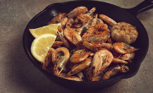 Fried shrimps, in a cast-iron pan, shrimps for beer, in a newspaper, on a gray table, there are no people