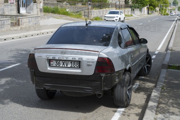Grey Opel Vectra with modern rims and rear damage parked on the outskirts of the city, Armenia