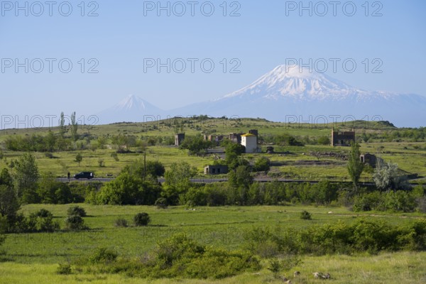 Wide green landscape with views of snow-capped mountains and scattered huts, view of large and small Ararat in Turkey, near Ujan, Aragazotn province, Armenia, AsiaArmenia, Asia