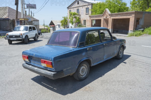 A blue car at an urban intersection on a clear sunny day, Lada 2107, also WAS-2107, VAZ-2107, Lada Nova or Lada Riva drives without a license plate, Armenia
