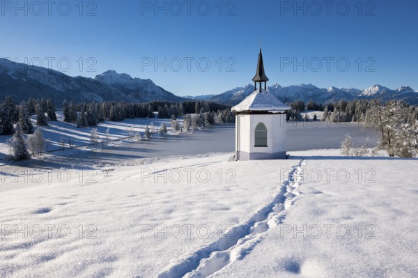 Chapel with footprints in the snow and a peaceful mountain landscape, Hegratsrieder See, near Füssen, Ostallgäu, Allgäu, Bavaria, Germany