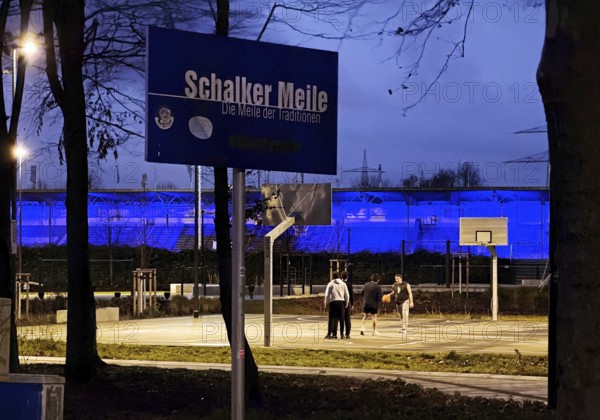 Schalker Meile sign at Ernst-Kuzorra-Platz in front of the royal blue illuminated Glückauf battle track, Gelsenkirchen, North Rhine-Westphalia, Germany