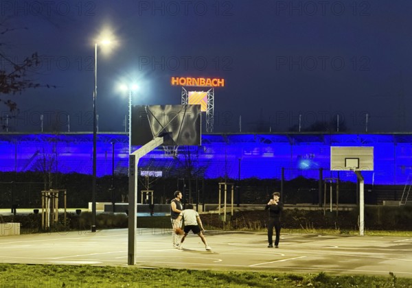 Men on Ernst-Kuzorra-Platz in front of the royal blue Glückauf battle track in the evening, Gelsenkirchen, North Rhine-Westphalia, Germany