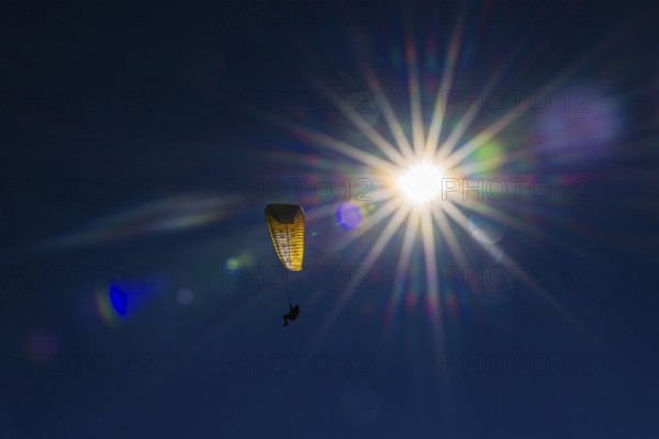 Paragliders against blue sky and bright sun, Val d'Anniviers, Valais Alps, Canton of Valais, Switzerland