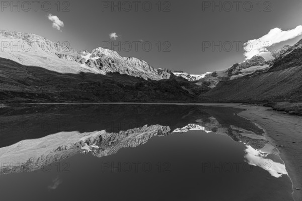 The Moiry glacier and mountain peaks are reflected in Lac de Chateaupre, black and white photo, Val d'Anniviers, Valais Alps, Canton of Valais, Switzerland