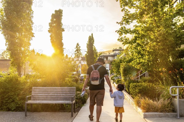 Father and son walking hand in hand at sunset in vancouver, cherishing quality moments together in a stunning urban landscape, surrounded by natures beauty and warm light