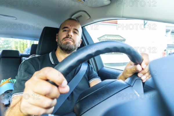 Caucasian man driving a modern car, wearing a seatbelt and holding the steering wheel, driving in the city of kamloops, british columbia, canada