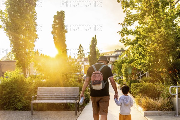 Father and son enjoying a leisurely stroll through a vancouver neighborhood at sunset, bathed in the golden light of the setting sun, creating a heartwarming scene of family bonding