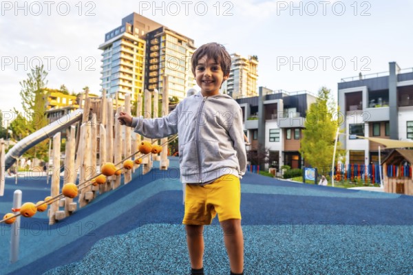 Smiling preschool child having fun in a colorful playground located in a residential area of vancouver, british columbia, promoting outdoor activities and urban childhood