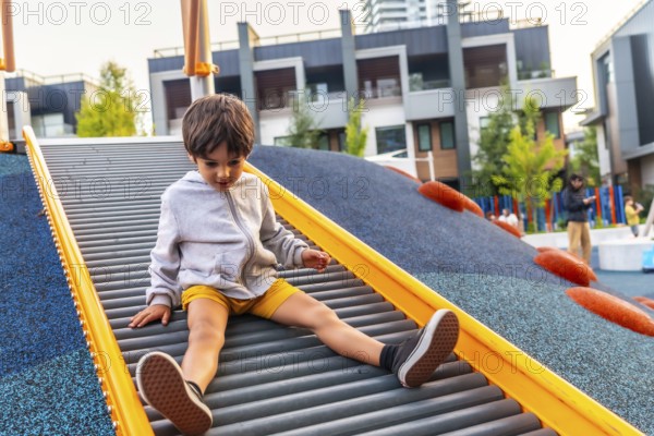 Preschool child having fun sliding down roller slide at playground in vancouver, british columbia, enjoying outdoor activities and playtime