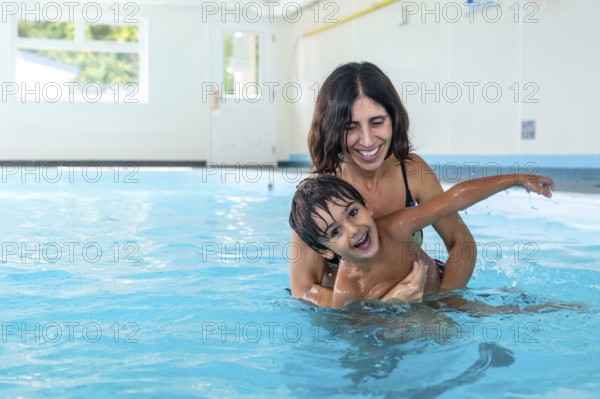 Mother and son smiling and playing together in a swimming pool, enjoying a fun filled leisure activity that fosters family bonding and promotes a healthy, active lifestyle