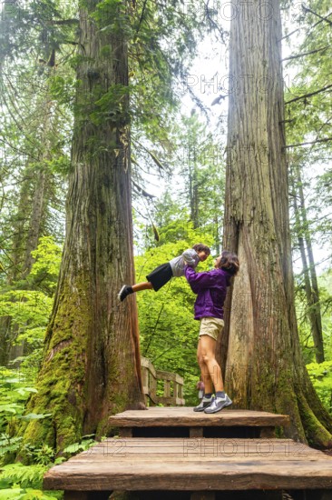 Mother and son sharing a joyful moment on the giant cedars boardwalk trail, surrounded by majestic cedar trees in mount revelstoke national park, british columbia