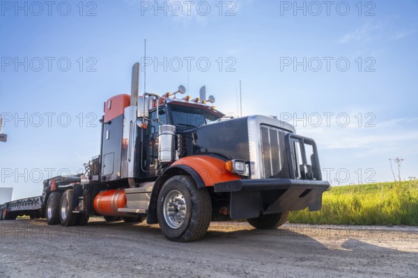 Powerful big rig semi truck with empty flatbed trailer parked on hemlock grove boardwalk in the canadian rockies, enjoying breathtaking sunset views