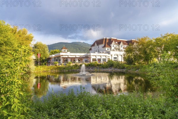 Picturesque salmon arm in british columbia features a luxurious hotel reflected in a serene pond, surrounded by lush greenery and majestic mountains