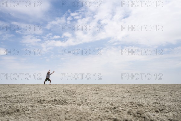 Symbolic picture, abstract, man raising his hands conjuring, on the Etosha pan, salt pan, Etosha National Park, Namibia