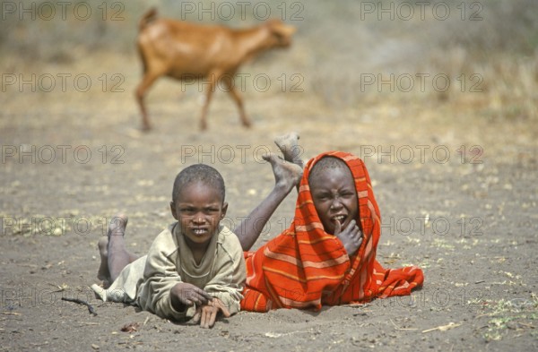 Maasai children lying on the ground in front of their village, goat, Ngorongoro Crater, Tanzania, Africa, June 2000, vintage, retro, old, historic