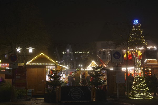 An atmospheric Christmas market in the dark with festively decorated huts and trees, Winterberg, North Rhine-Westphalia, Germany