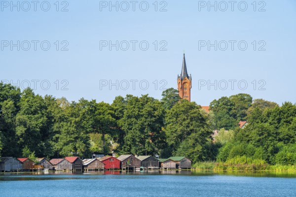 View across the Haussee to the town church and colorful boathouses on stilts, Feldberg, Feldberg Lake District, Mecklenburg-Western Pomerania, Germany