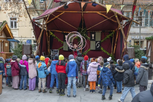 A group of children watches an acrobat on stage, Historischer Christmas market am Neustädter church square, Erlangen, Middle Franconia, Bavaria, Germany