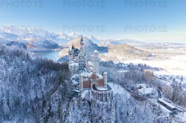 Fairytale castle Neuschwanstein in snowy landscape surrounded by majestic mountains and blue skies, Schwangau near Füssen, Ostallgäu, Allgäu, Bavaria, Germany