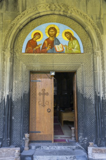 Opened wooden door with religious icon above, embedded in ancient stone decorated arch, Akhtala monastery, Akhtala, town of Akhtala, Lorikeet province, Armenia